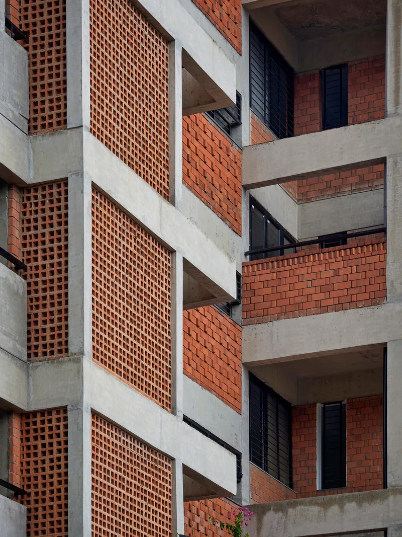 Facade detail of concrete frame with perforated terracotta brick screens and recessed balconies