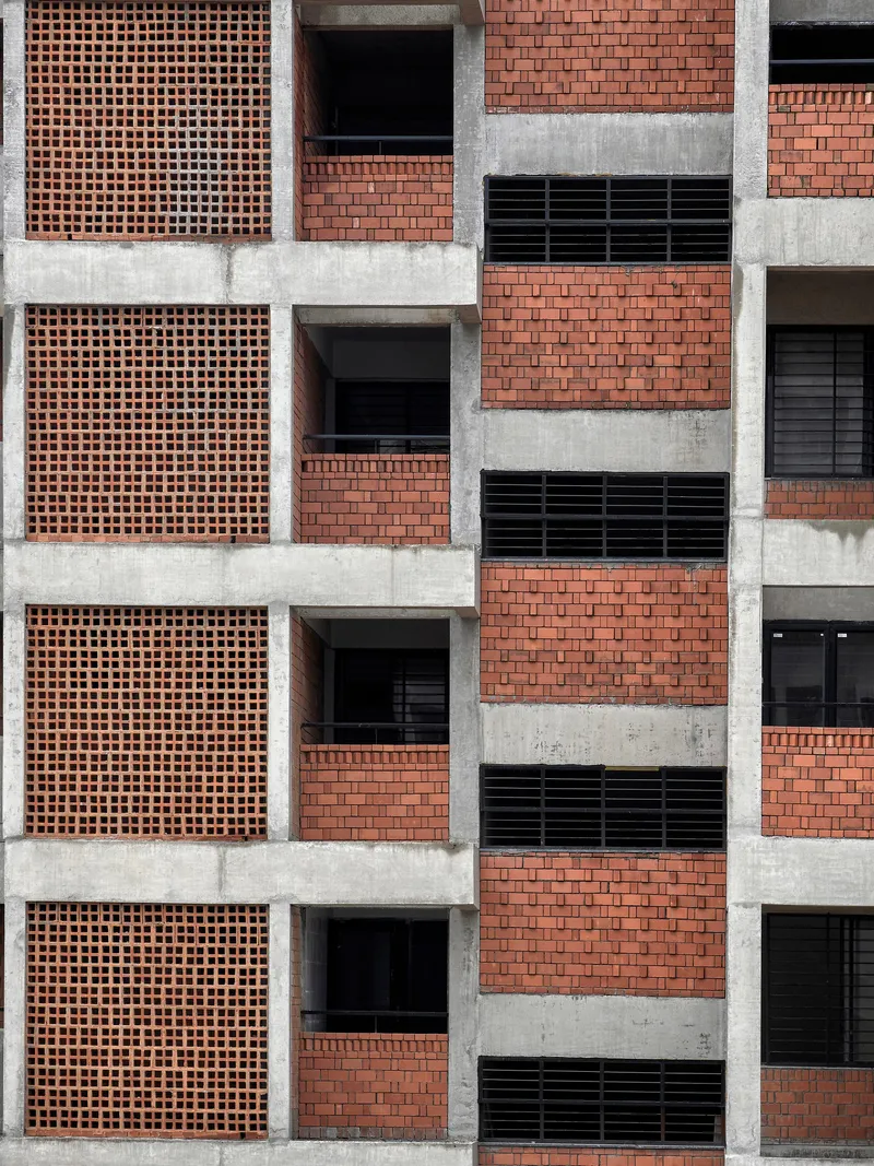 Flat frontal view of the gridded facade with terracotta brick screens and horizontal concrete bands