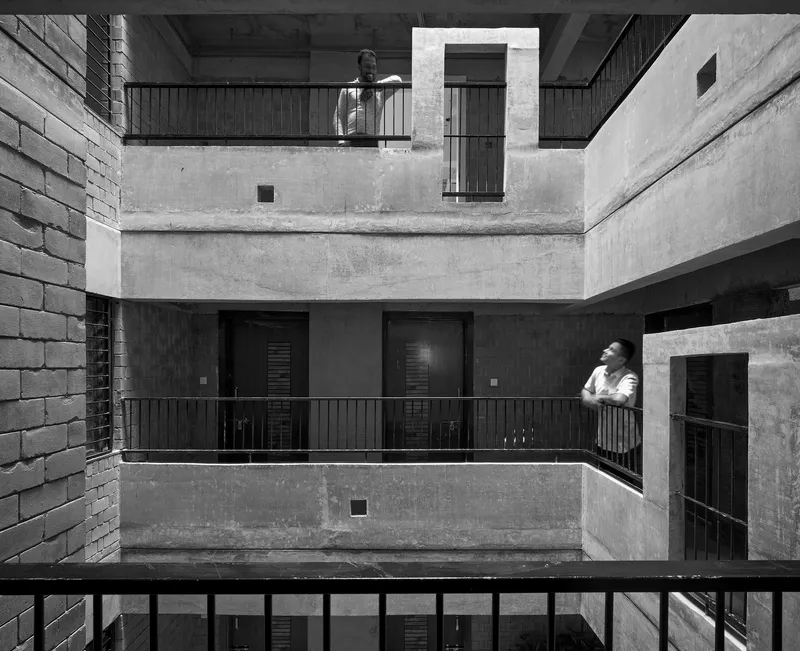 Black and white view of the interior courtyard with stacked balconies and a figure standing on one level