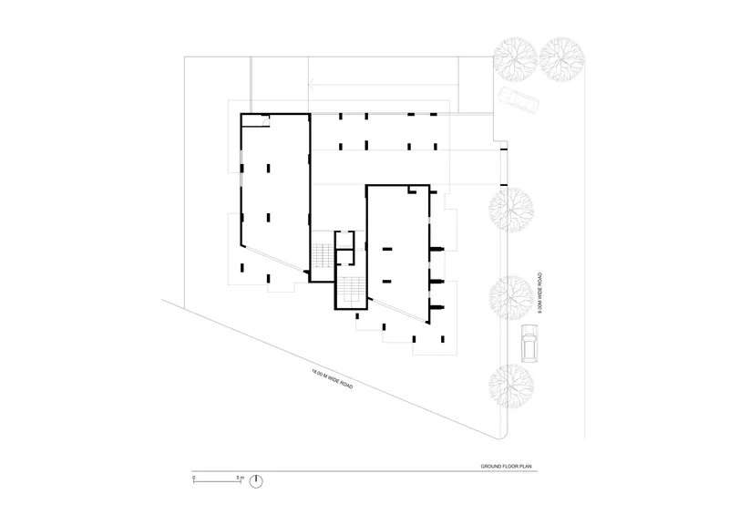 Ground floor plan drawing showing two L-shaped volumes connected by a central stairwell with adjacent street trees