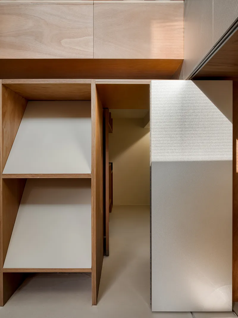 Close-up of angled plywood shelves with white laminate surfaces casting diagonal shadows