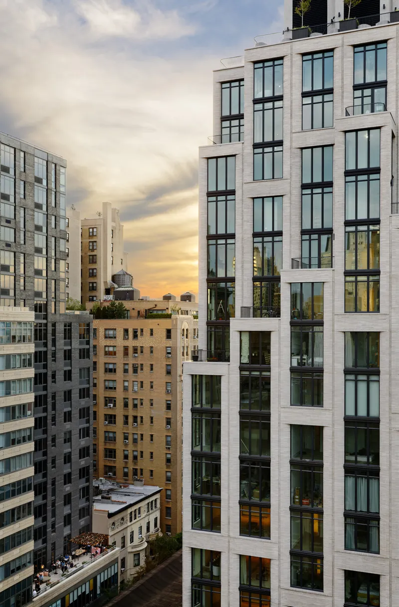 Oblique view of the tower facade with balconies and wide windows facing a courtyard at dusk
