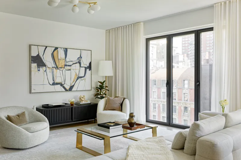 Living room with curved sofas and black-framed windows overlooking neighboring buildings