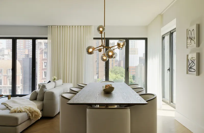 Dining area with brass chandelier above table near window with living room beyond
