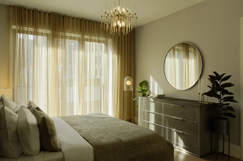 Bedroom with layered curtains filtering afternoon sunlight across the bed and dresser