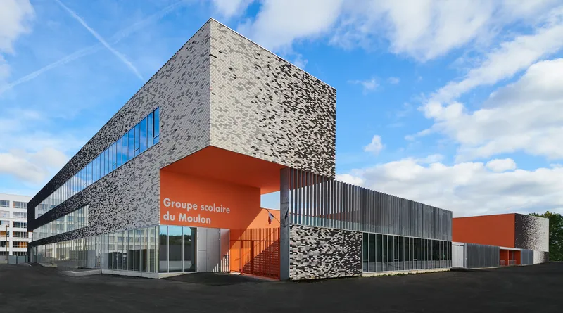 Corner view of the perforated grey facade with orange entry volume and glazed ground floor