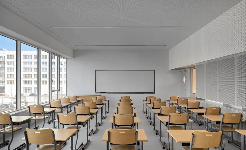 Classroom with rows of wooden desks and chairs facing a whiteboard mounted on the wall