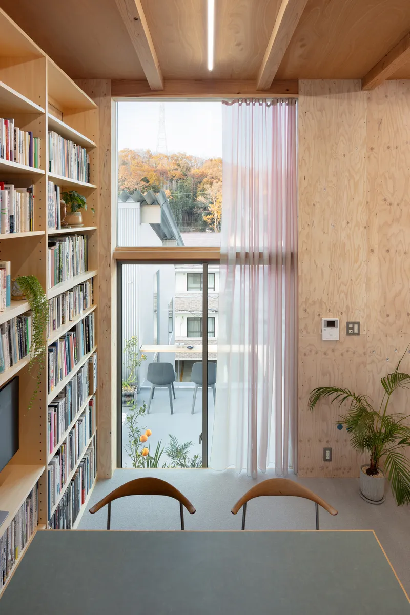 Study nook with floor-to-ceiling bookshelves and full-height window overlooking autumn foliage
