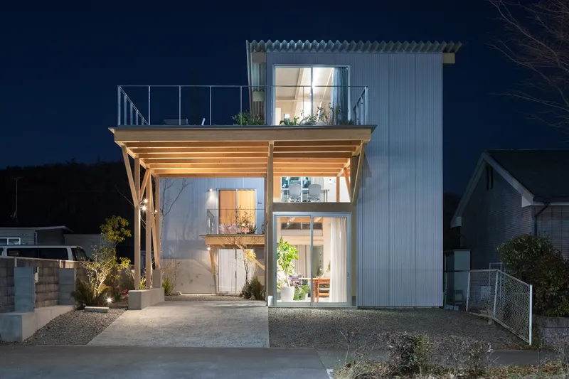 Night view of the timber-framed facade with exposed structural beams and floor-to-ceiling glazing under a dark sky