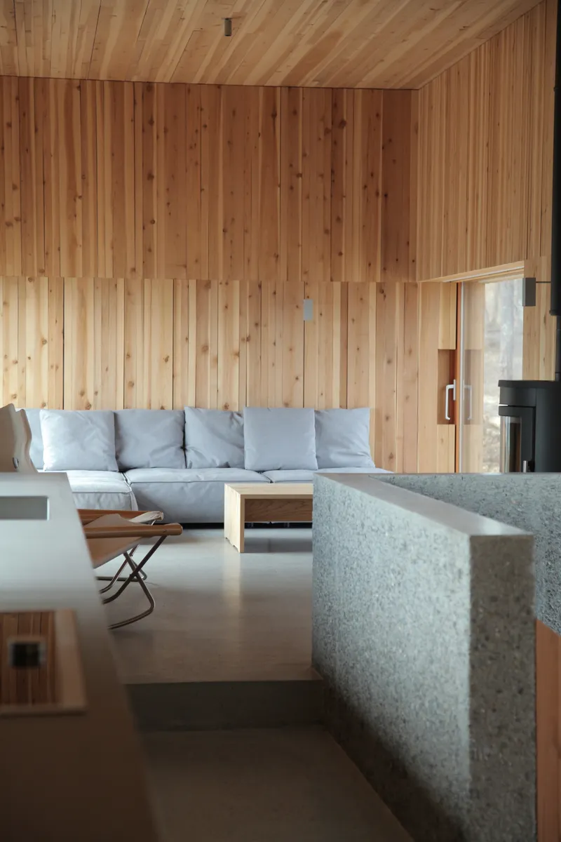 Living space showing terrazzo kitchen counter edge with timber wall and ceiling paneling beyond