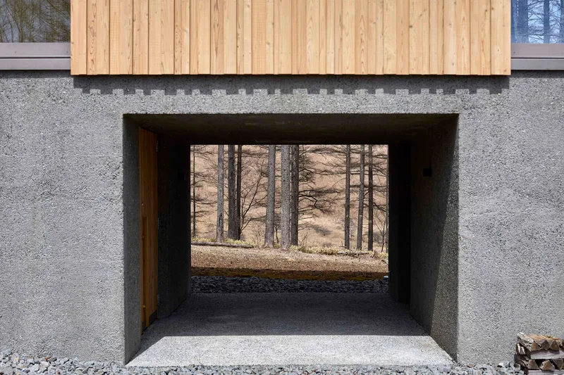 Deep window recess framing view of the forest floor through concrete walls