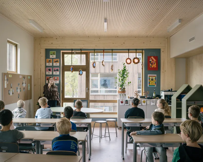 Classroom with timber slatted ceiling and students seated at desks facing a teacher by the window