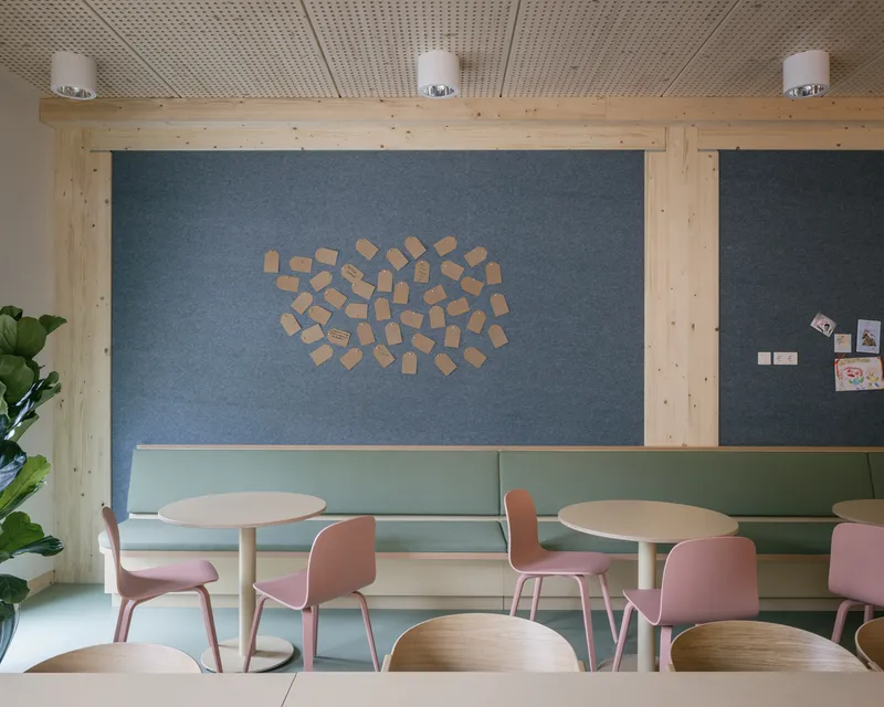 Dining area with built-in bench seating and cork notice tiles arranged on the blue wall