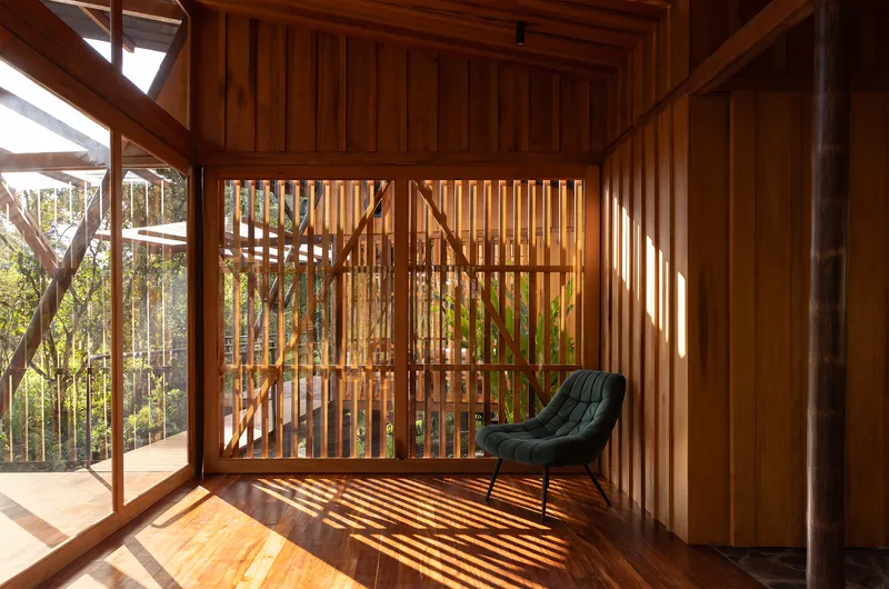 Interior corner with vertical timber slat partition casting shadows on wooden floor