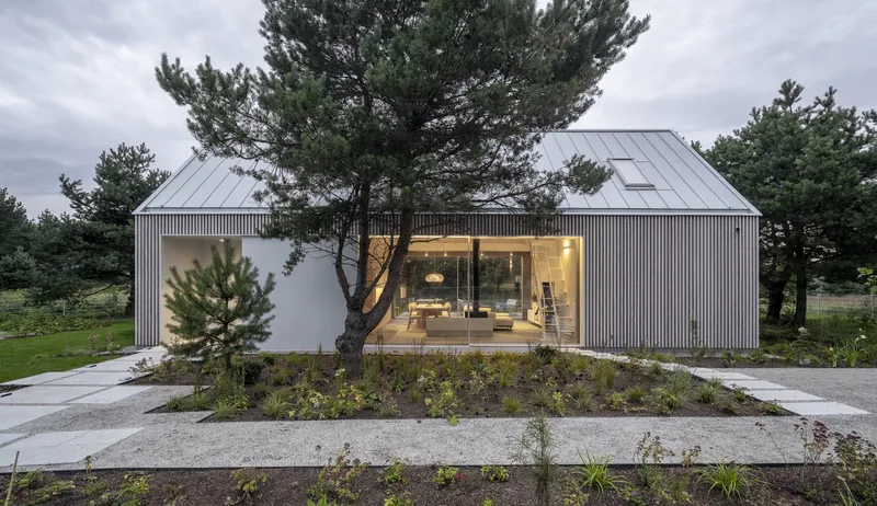 Twin gabled volumes clad in vertical timber with glazed living space and surrounding planted beds
