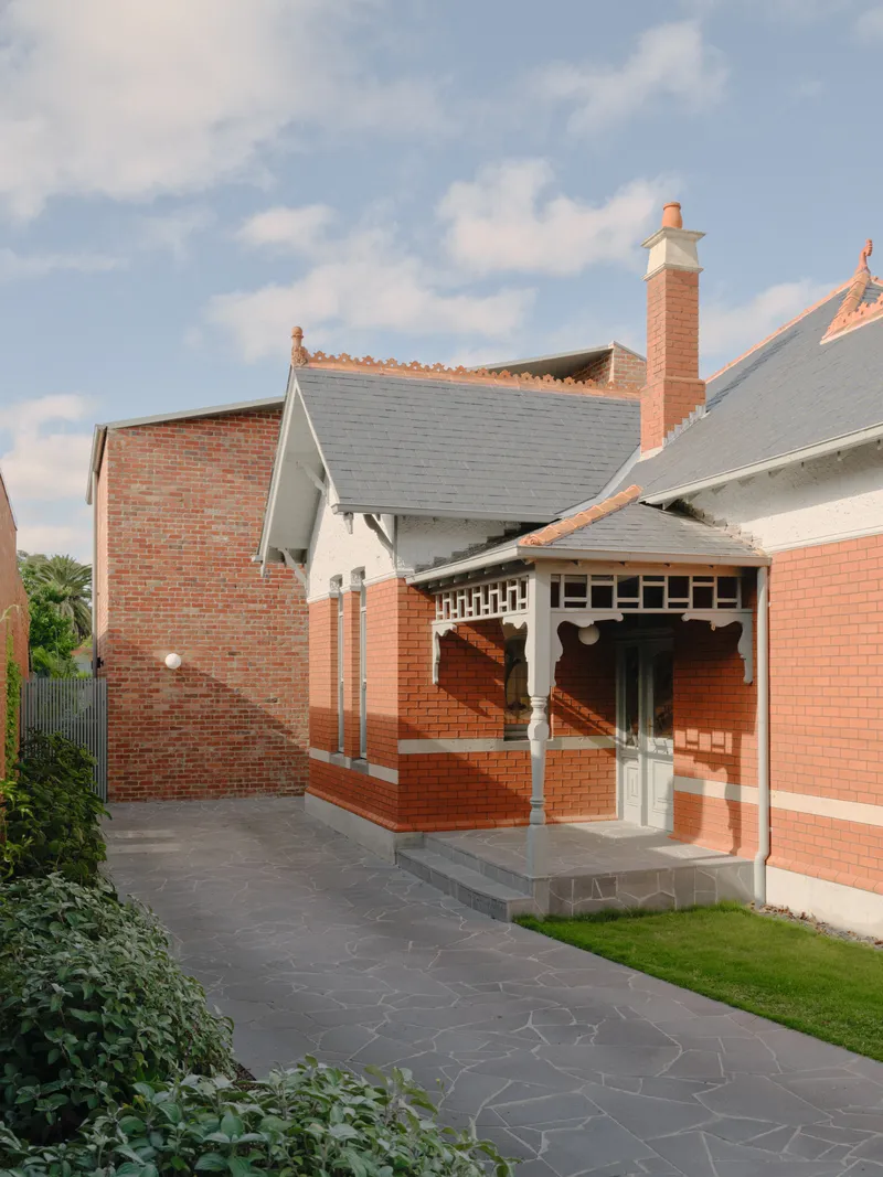 Rear courtyard showing red brick porch with decorative timber brackets and dark stone paving