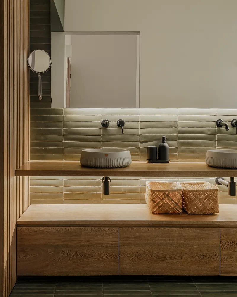 Bathroom vanity with timber countertop and cream ribbed tile backsplash under soft lighting