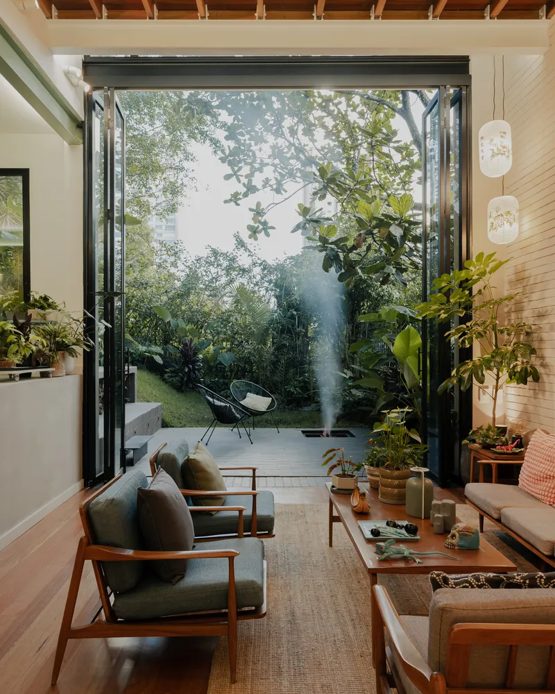 Living room view through fully opened folding glass doors to courtyard garden in morning mist