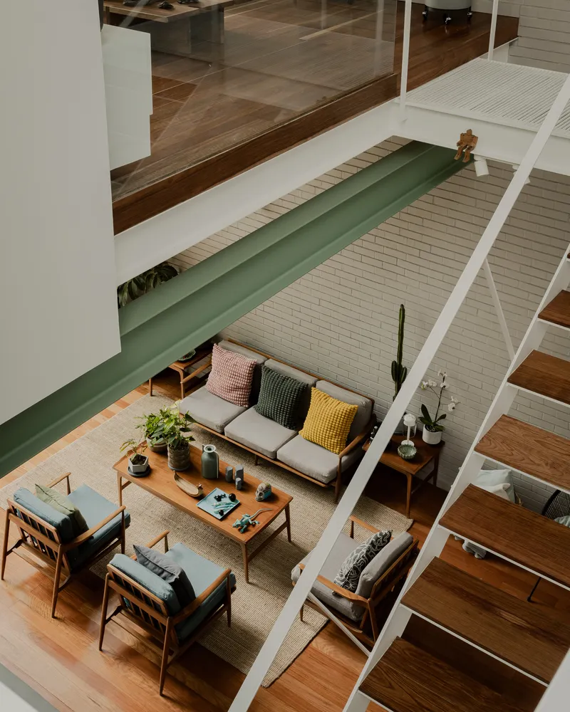 Overhead view of the living room with exposed timber beams and a green steel bridge