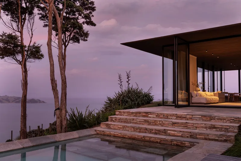 Terrace with layered stone steps and infinity pool overlooking the ocean at dusk