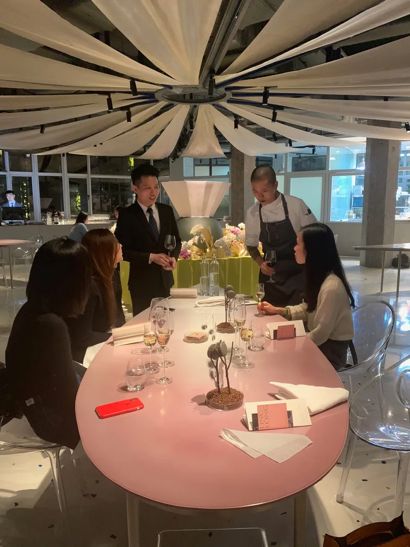 Diners and staff gathered around a pink table beneath the radial fabric ceiling installation