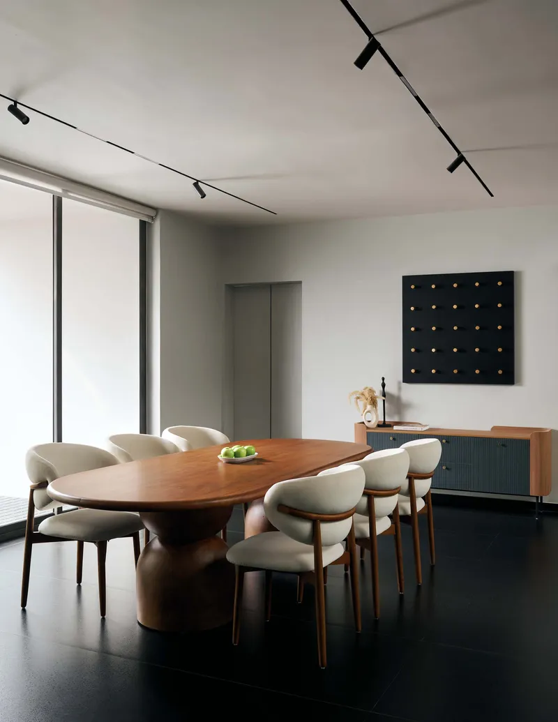 Dining room with oval timber table and upholstered chairs beneath black track lighting