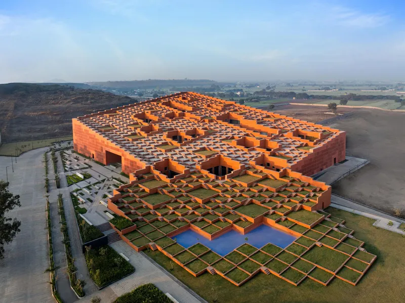 Aerial view of the terraced orange brick complex with framed courtyards and a central reflecting pool