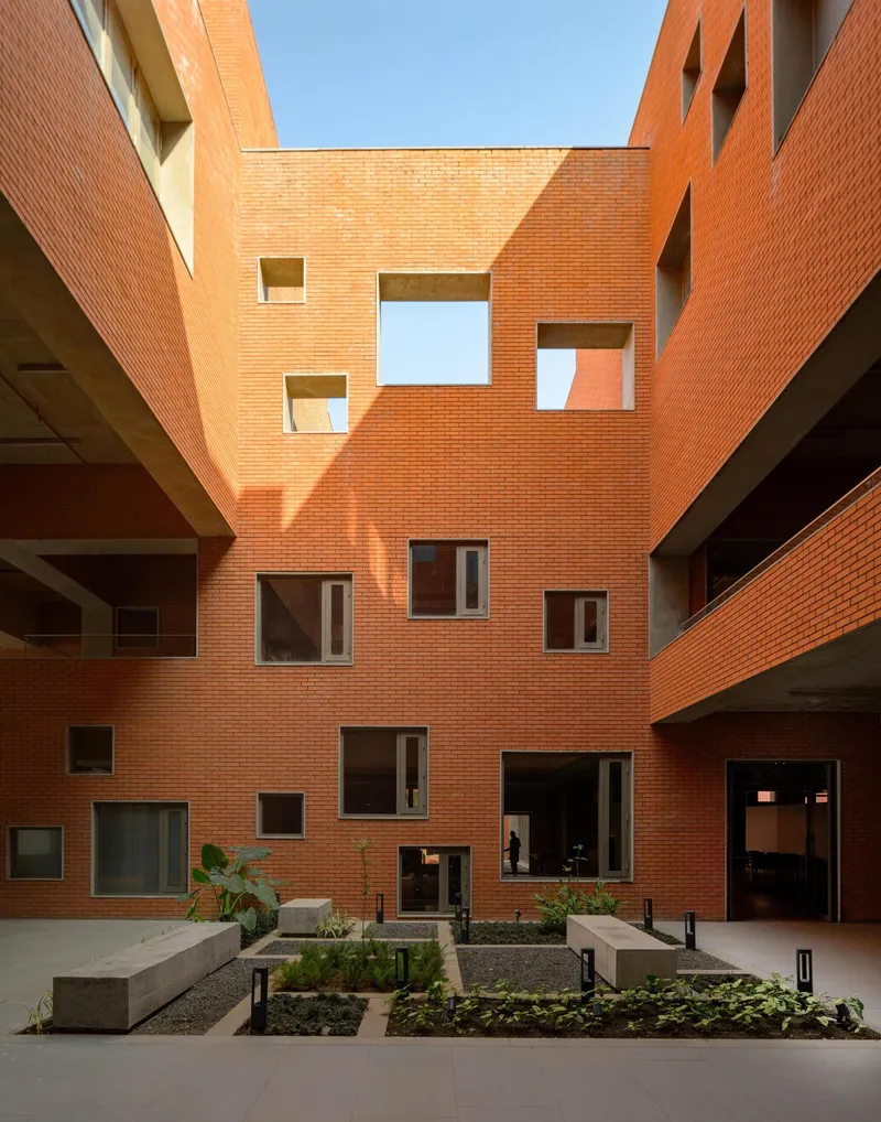 Interior courtyard framed by orange brick walls with scattered windows and planted beds on the ground