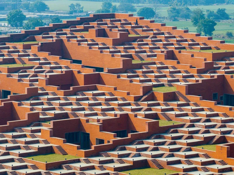 Aerial view of terraced orange and brown brick roofscape with stepped volumes and planted courtyards
