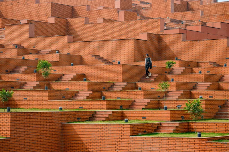 Terraced brick amphitheater with cantilevered steps and planted alcoves where a person climbs