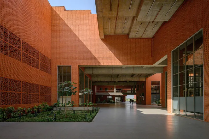 Ground-level view of a covered passageway with exposed concrete beams and planted landscape beds