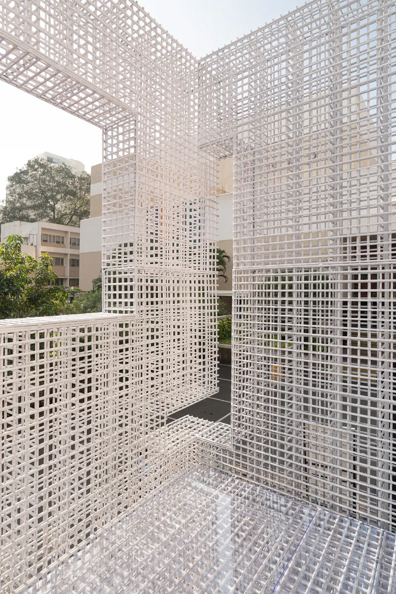 Corner courtyard enclosed by white lattice mesh walls and ceiling open to sky