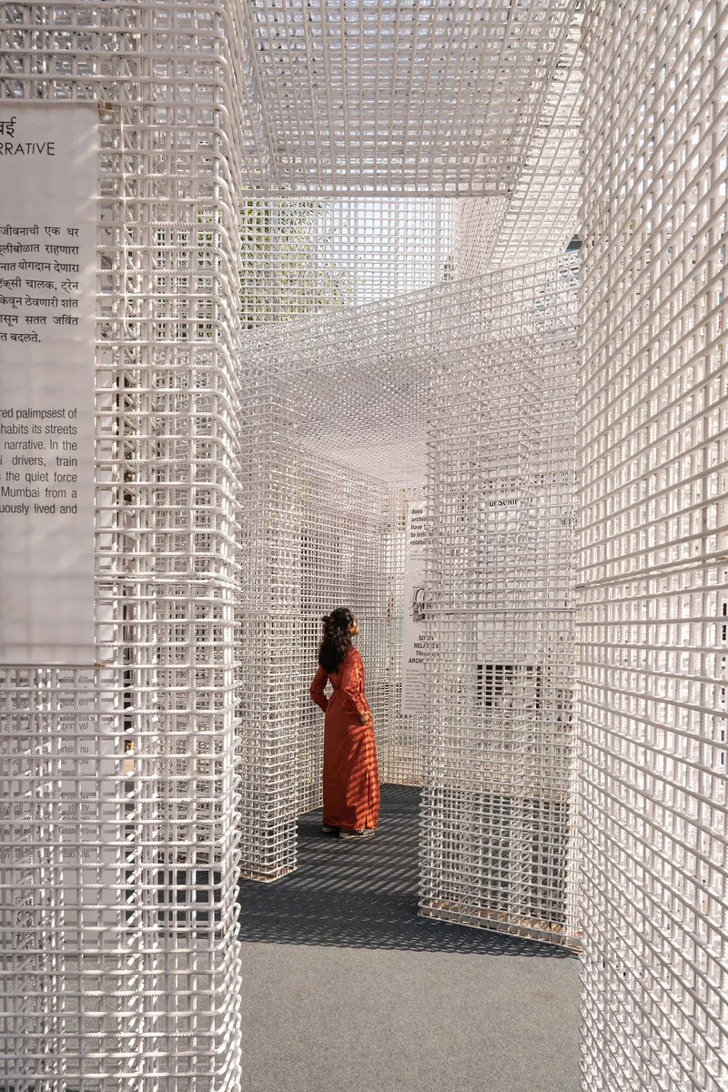 Interior chamber formed by white lattice walls with a visitor in orange standing beneath filtered daylight