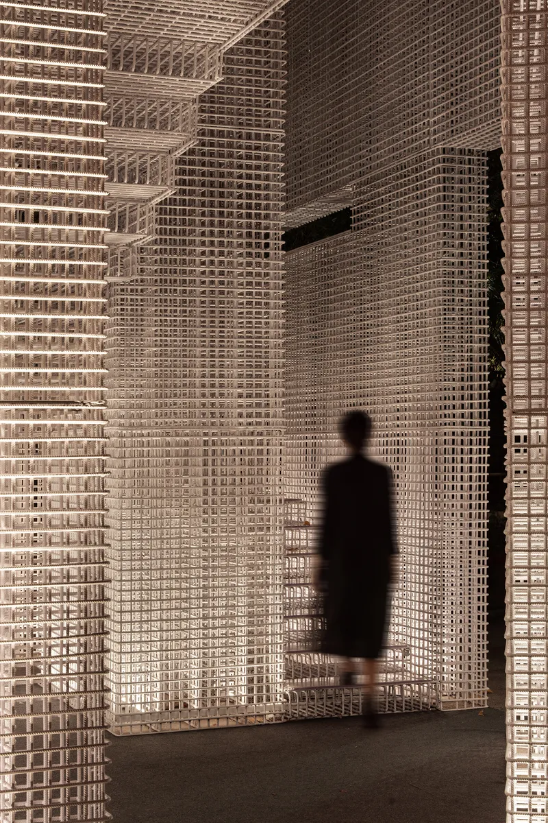 Shadow of a visitor cast on translucent white lattice walls at dusk or under warm lighting