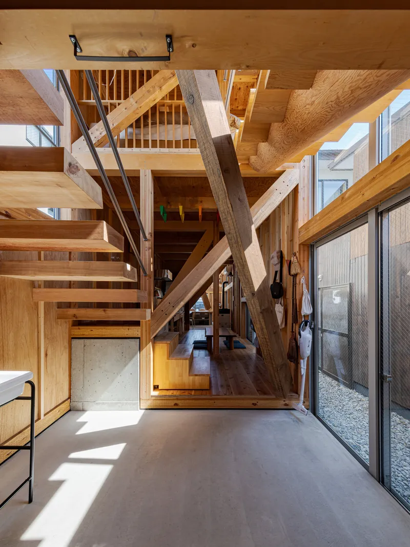 Ground floor entry with polished concrete floor and timber stair crossing diagonal structural members