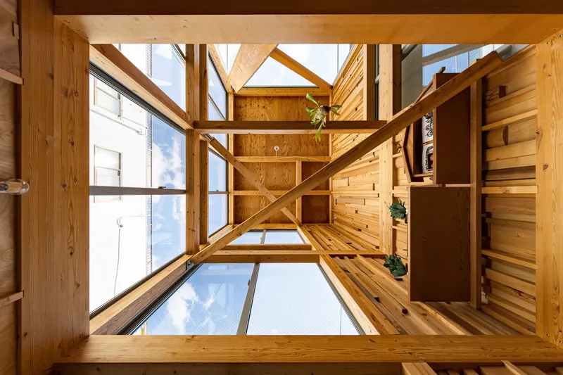 Upward view through the central void showing timber framing and glass floor panels