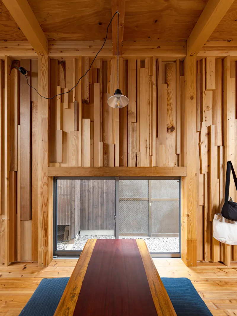 Interior room with variegated timber wall cladding and a pendant lamp above a two-tone table
