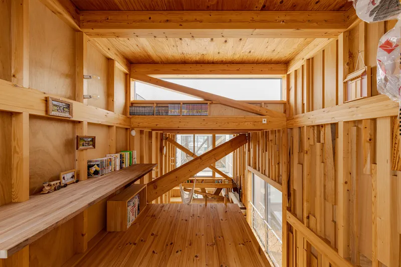 Upper-level study space with timber ceiling and diagonal structural brace overlooking the dining area below