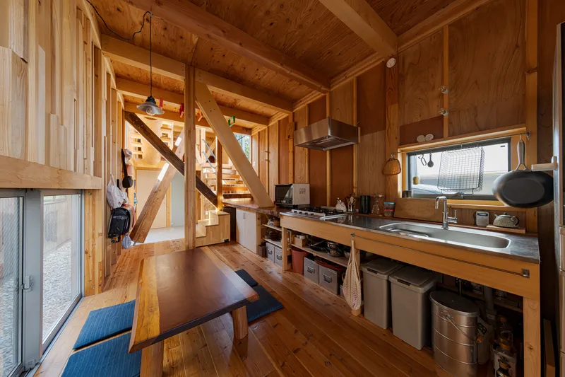 Open kitchen with timber countertop and diagonal bracing visible beyond the staircase