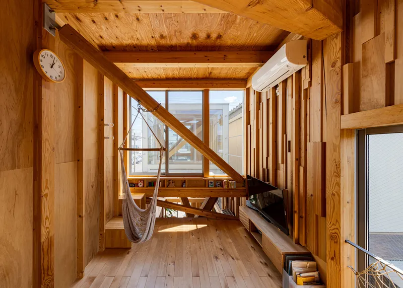 Upper-level room with exposed timber beams, a suspended hammock, and high clerestory windows