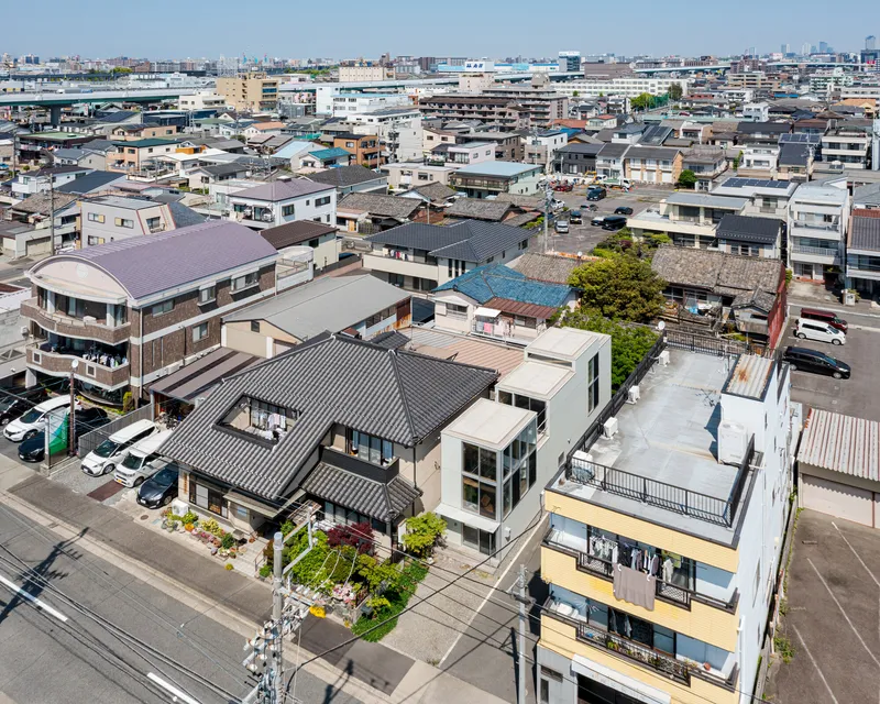 Aerial view of a white box structure among dense low-rise residential rooftops on a clear day