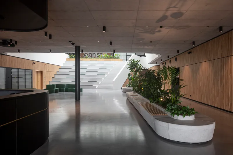 Reception lobby with floating staircase, curved planter beds, and polished concrete floor