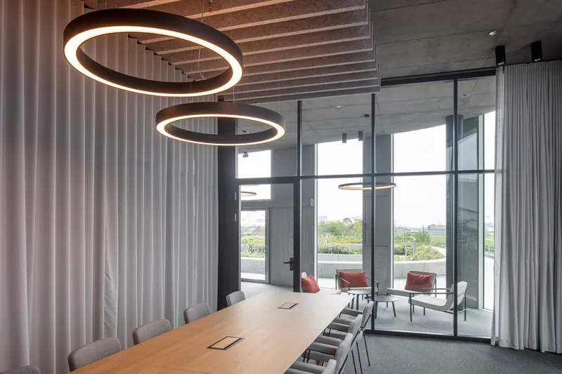 Conference room with a timber table, twin circular pendant lights, and glazed walls opening to a terrace