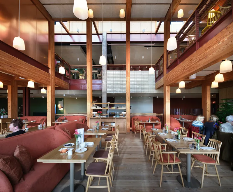 Dining area with timber frame structure, pendant lights, and red upholstered banquette seating
