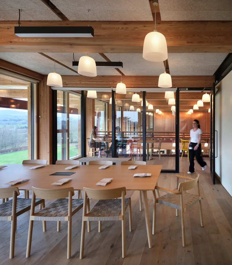 Private dining room with long table, pendant lights, and view to landscape at dusk