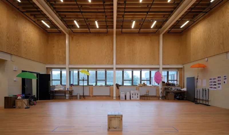 Large studio space with plywood walls, exposed timber ceiling structure, and continuous clerestory windows