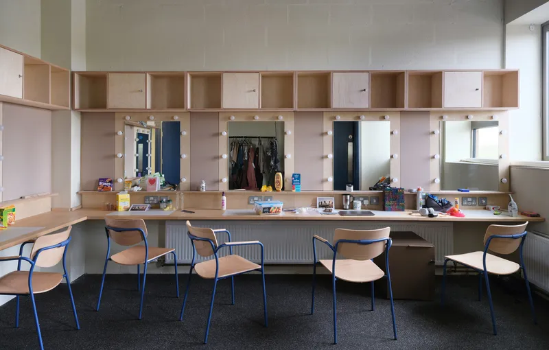 Built-in plywood vanity unit with integrated mirrors, storage cubbies, and a row of chairs below
