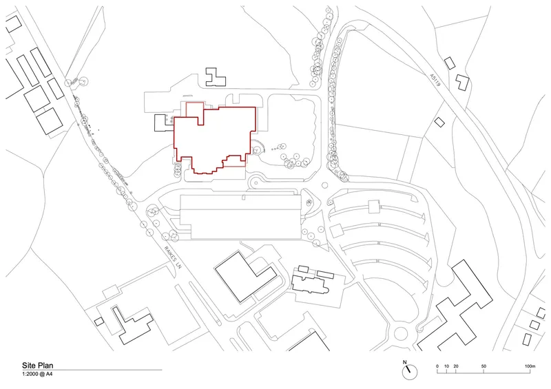 Site plan drawing showing building footprint adjacent to curving roads and tree-lined paths