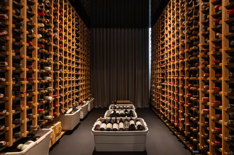 Wine cellar with floor-to-ceiling timber racking illuminated by vertical strip lighting