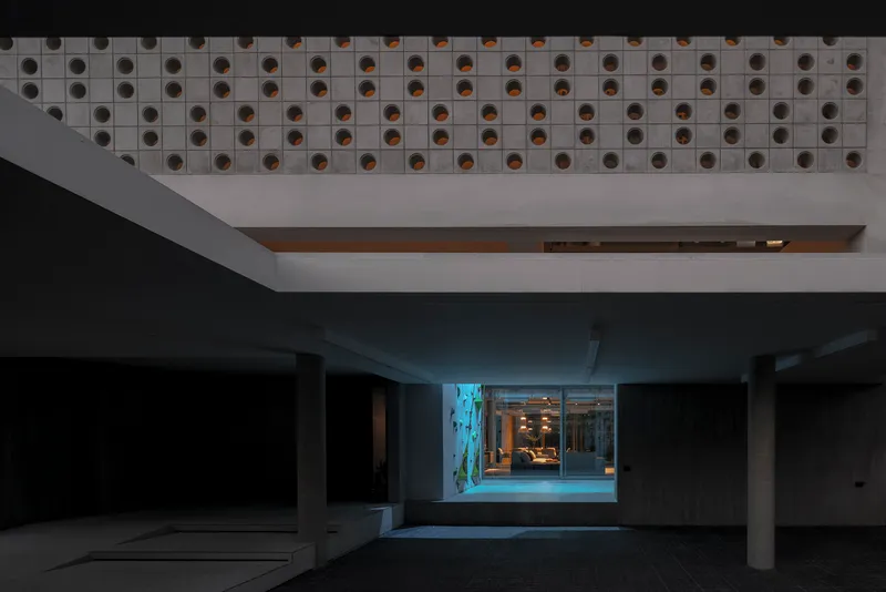Parking garage interior at dusk with perforated ceiling soffit and illuminated entrance beyond